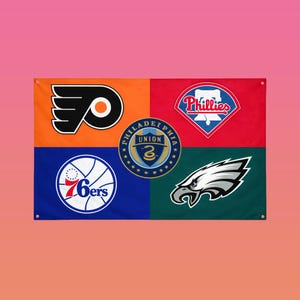 May include: A rectangular flag featuring four colored quadrants with Philadelphia sports team logos. The orange section displays the Flyers logo, red shows the Phillies, blue features the 76ers, and green contains the Eagles logo with a central Union crest.