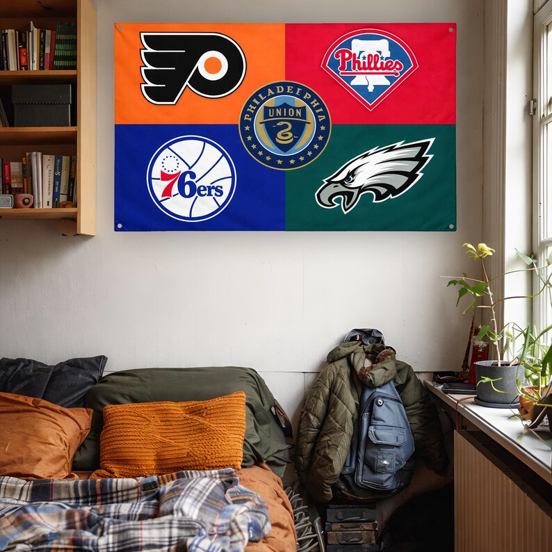 May include: A rectangular wall flag featuring four colored quadrants with Philadelphia sports team logos. The top left is orange with the Flyers logo, top right is red with the Phillies logo, bottom left is blue with the 76ers logo, and bottom right is green with the Eagles logo. A circular Philadelphia Union crest is centered.