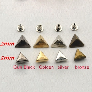 Pode incluir: Oito tachas de metal em forma de pirâmide em quatro cores diferentes: preto fosco, dourado, prateado e bronze. As tachas medem 9,5 mm e 12 mm.