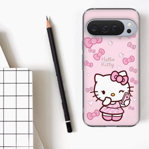 Puede incluir: Una funda de tel&eacute;fono rosa con el personaje de Hello Kitty sosteniendo un tel&eacute;fono. La funda tiene un patr&oacute;n repetido de lazos y corazones rosas. Un l&aacute;piz negro y un cuaderno blanco con un patr&oacute;n de cuadr&iacute;cula tambi&eacute;n est&aacute;n en la imagen.