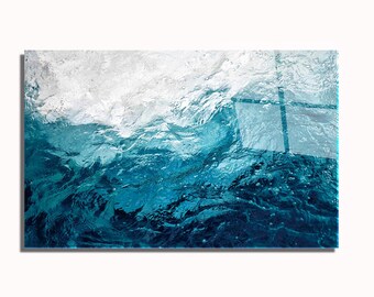 May include: Abstract art print featuring a close-up view of water. The image showcases shades of blue and white, with a focus on the texture and movement of the water's surface. The artwork is mounted on a rectangular frame.