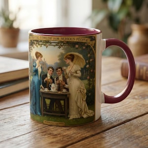 May include: White ceramic mug with a burgundy interior and handle. The mug features a vintage illustration of a group of people in period clothing, with the text "A TRIVIAL COMEDY FOR SERIOUS PEOPLE".
