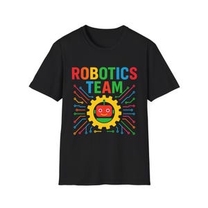 Puede incluir: Camiseta negra con la frase "ROBOTICS TEAM" en rojo, verde y azul. Un engranaje amarillo con una cara de robot roja está en el centro, rodeado de diseños de circuitos coloridos.