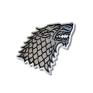 Puede incluir: Parche bordado con el emblema del lobo huargo de la Casa Stark de una popular serie de fantasía. El parche tiene una combinación de colores gris y negro con un borde blanco. La cabeza del lobo está orientada hacia la derecha, con la boca abierta.