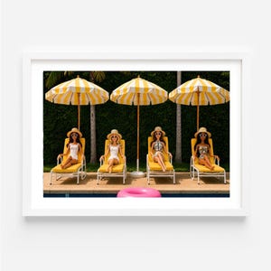 May include: Four dolls wearing straw hats and sunglasses sit on yellow lounge chairs under three yellow and white striped umbrellas. A pink inflatable ring floats in the pool water in the foreground, set against a backdrop of green hedges.