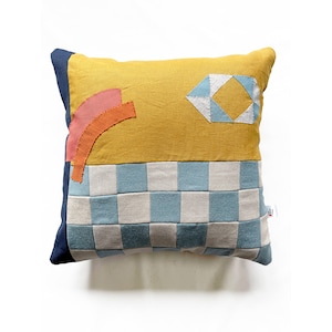 Puede incluir: Una almohada de tiro con estampado geométrico amarillo, azul y naranja con un diseño a cuadros en la mitad inferior.