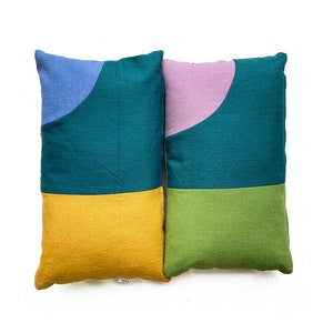 Peut inclure: Deux coussins d&eacute;coratifs avec des motifs g&eacute;om&eacute;triques. Un coussin est turquoise, jaune et bleu. L'autre coussin est turquoise, vert et violet.
