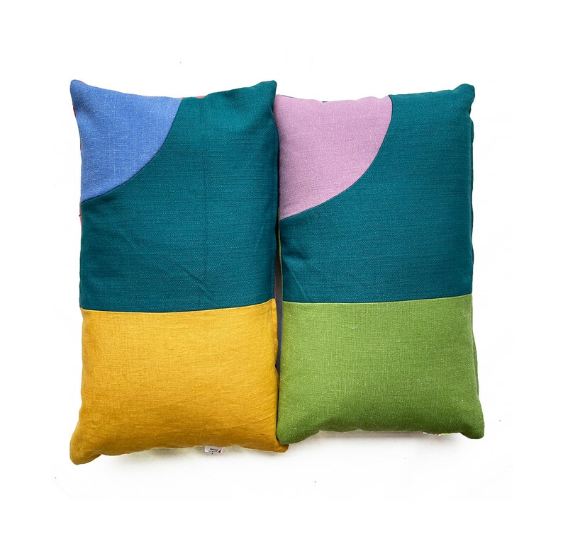 Peut inclure: Deux coussins d&eacute;coratifs avec des motifs g&eacute;om&eacute;triques. Un coussin est turquoise, jaune et bleu. L'autre coussin est turquoise, vert et violet.