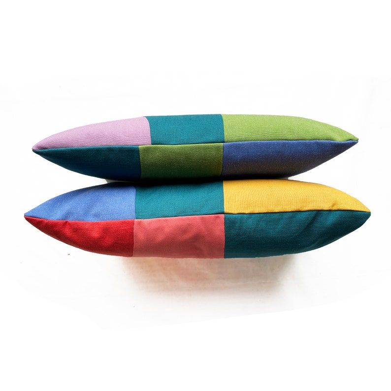 Peut inclure: Deux coussins rectangulaires avec un motif patchwork. Le coussin du haut est violet, vert et bleu. Le coussin du bas est bleu, vert, rouge et rose.