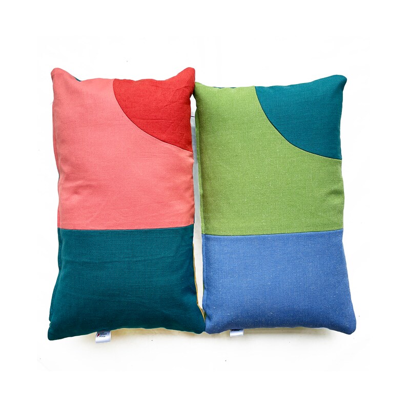 Peut inclure: Deux coussins d&eacute;coratifs avec des motifs g&eacute;om&eacute;triques. Un coussin est rose, rouge et vert, et l'autre est vert, bleu et turquoise.