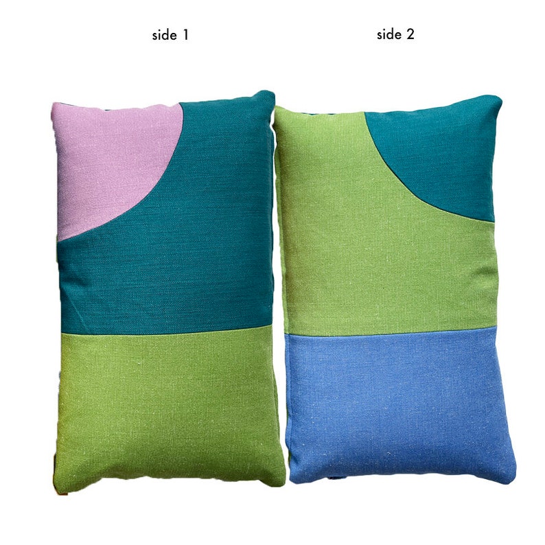 Peut inclure: Deux oreillers rectangulaires avec des motifs g&eacute;om&eacute;triques diff&eacute;rents de chaque c&ocirc;t&eacute;. Un c&ocirc;t&eacute; pr&eacute;sente un fond vert sarcelle avec une forme incurv&eacute;e rose et verte. L'autre c&ocirc;t&eacute; pr&eacute;sente un fond vert avec une forme incurv&eacute;e bleue et verte.