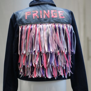 Fabulous, opulent, upcycled denim jacket with 3 tiers of pink, white and lilac ribbon fringing and the word FRINGE, size 16
