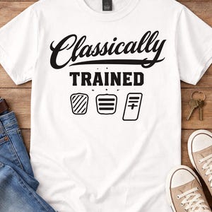 Könnte beinhalten: Weißes T-Shirt mit dem Schriftzug "Classically Trained" in schwarzer Schrift und Blockbuchstaben. Darunter befinden sich drei schwarz-weiße grafische Symbole. Das Shirt wird mit blauen Jeans, Sonnenbrille, Schlüsseln und Leinenschuhen präsentiert.
