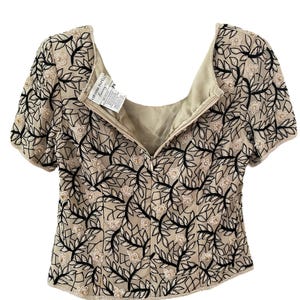 Puede incluir: Top beige de manga corta con cuello cuadrado. El top est&aacute; adornado con un dise&ntilde;o floral en blanco y negro. La etiqueta dice "Adrianna Papell". El top tiene cierre de cremallera en la espalda.