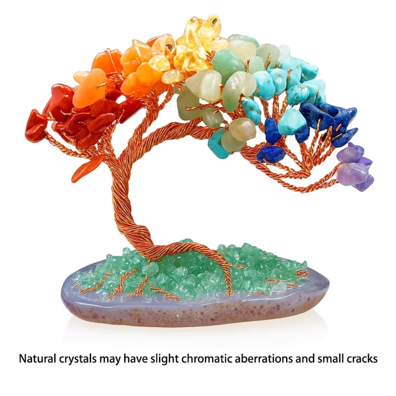 May include: A decorative tree sculpture made of copper wire and colorful gemstones. The tree features a trunk and branches with various colored stones, including red, orange, yellow, green, blue, and purple. The base is a gray oval with green stones. Text: Natural crystals may have slight chromatic aberrations and small cracks.
