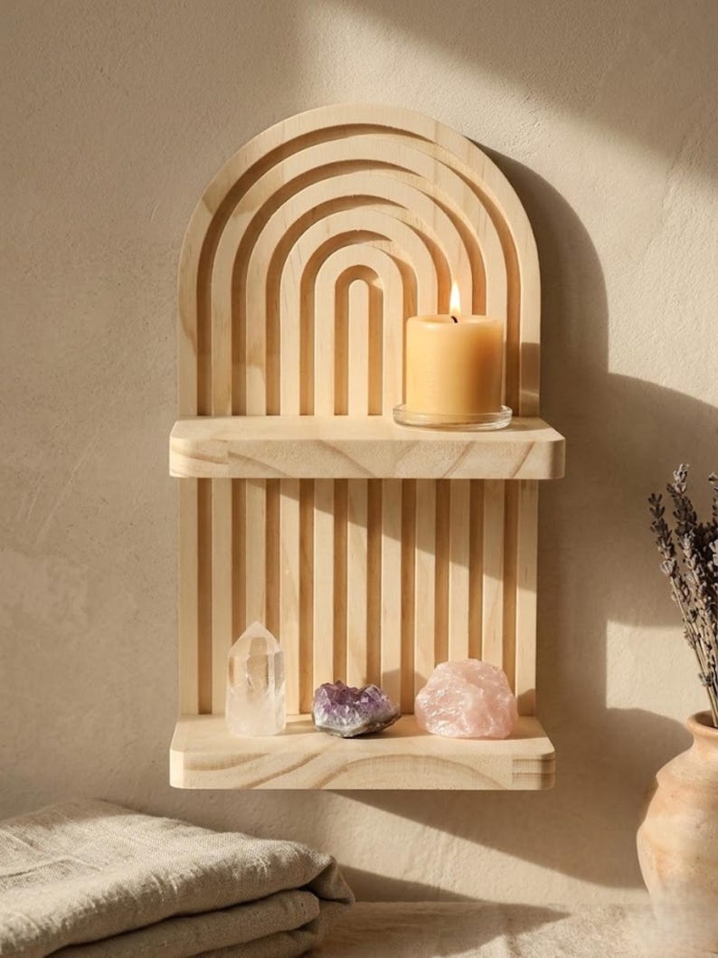 Puede incluir: Una estanter&iacute;a de pared de madera con un dise&ntilde;o de arco iris. La estanter&iacute;a contiene una vela encendida, un cristal de cuarzo transparente, amatista y un cuarzo rosa. La estanter&iacute;a es de madera clara y tiene un acabado natural. Un jarr&oacute;n con lavanda est&aacute; a la derecha.