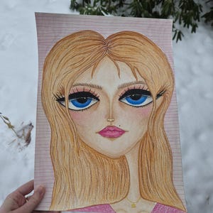 May include: A colored pencil drawing of a woman's face with large blue eyes, long eyelashes, and blonde hair. The woman is wearing a pink top and a gold necklace. The drawing is on lined paper.