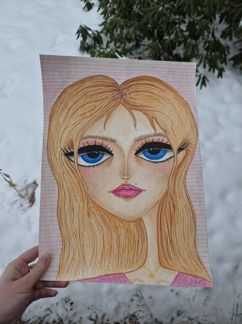 May include: A colored pencil drawing of a woman's face with large blue eyes, long eyelashes, and blonde hair. The woman is wearing a pink top and a gold necklace. The drawing is on lined paper.