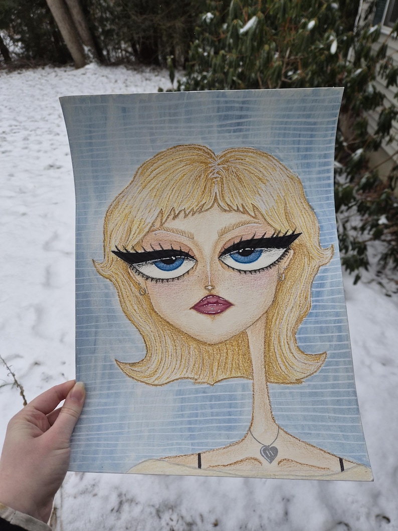 May include: A watercolor portrait of a woman with blonde hair, blue eyes, and a teardrop. The artwork features a thin neck and a heart pendant necklace. The background is a light blue with vertical lines.