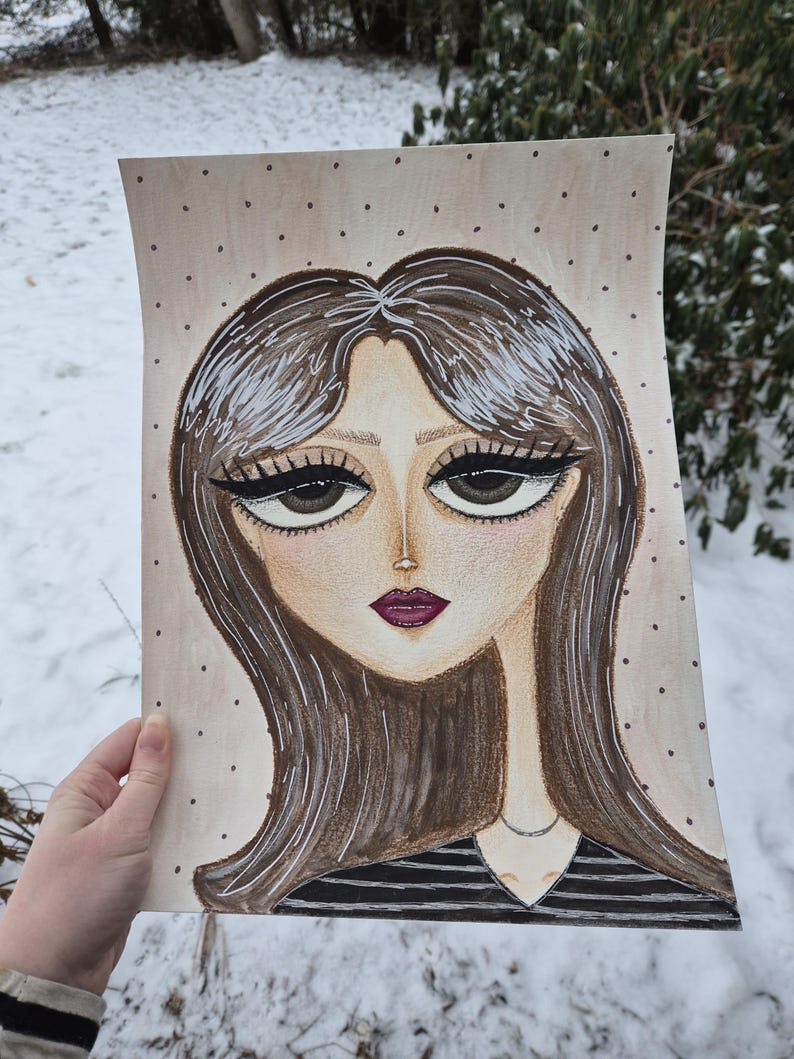 May include: A hand-drawn portrait of a woman with long brown hair and large eyes. The artwork features a black and white striped top and a delicate silver necklace. The background is a light beige with small, evenly spaced dark dots.