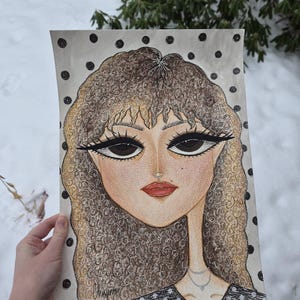 May include: A hand-drawn portrait of a woman with large eyes, red lips, and curly hair. The artwork features a polka-dot background and a delicate necklace. The artist's signature is visible. The color palette includes beige, brown, and black.