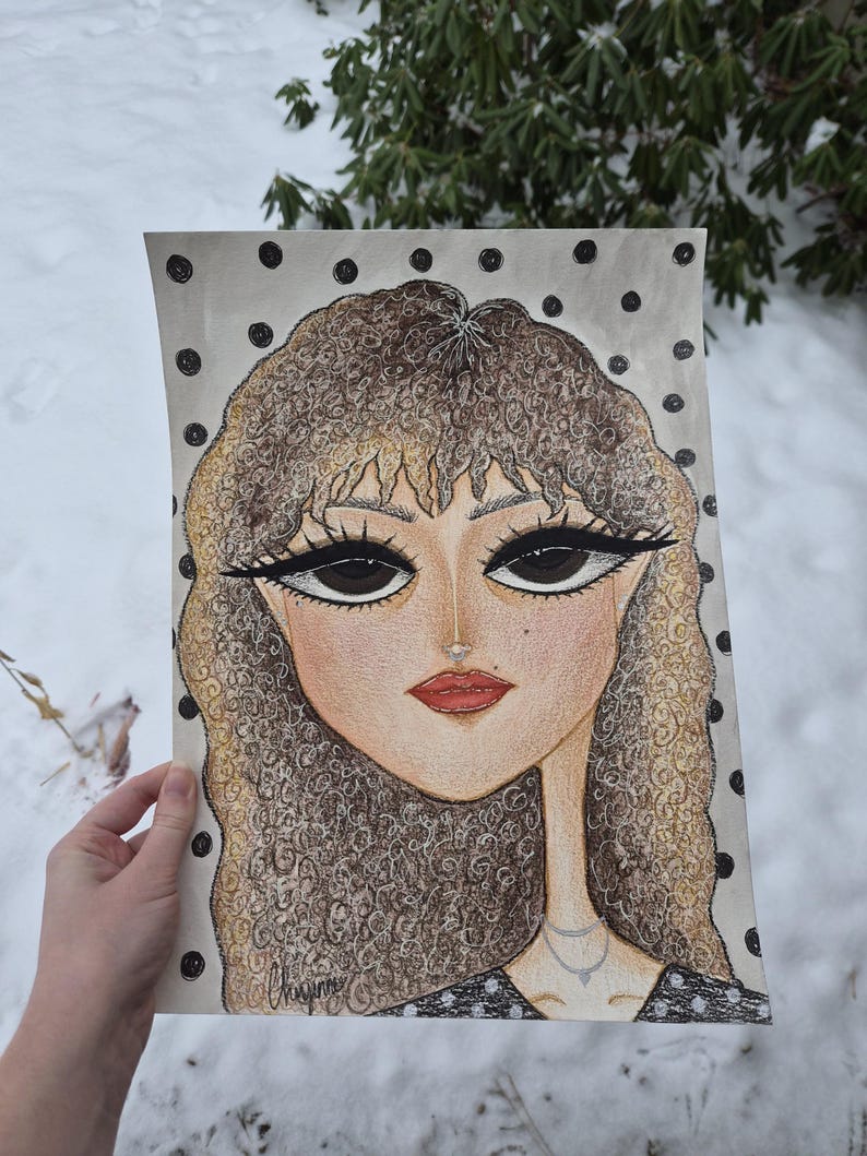 May include: A hand-drawn portrait of a woman with large eyes, red lips, and curly hair. The artwork features a polka-dot background and a delicate necklace. The artist's signature is visible. The color palette includes beige, brown, and black.