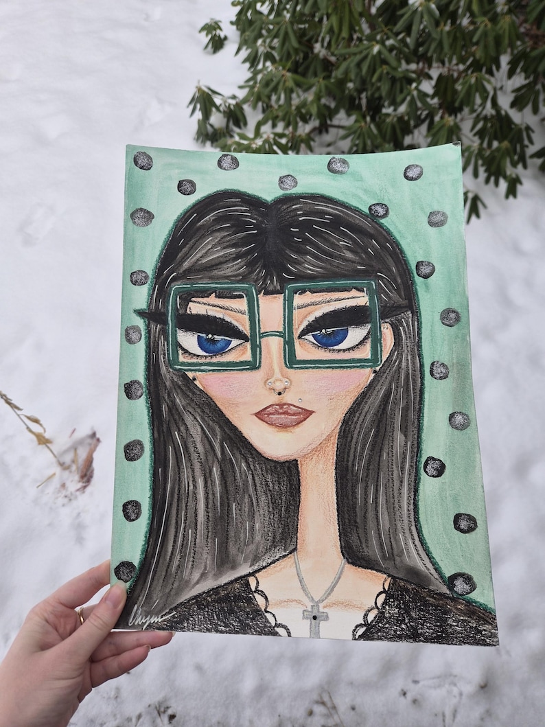 May include: A hand-drawn portrait of a woman with long black hair, blue eyes, and square green glasses. The artwork features a mint green background with black polka dots. The woman is wearing a black top and a silver cross necklace.