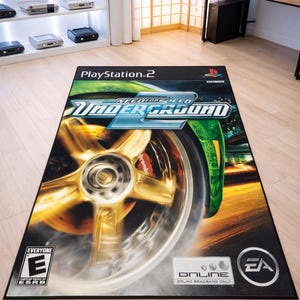 May include: A rectangular area rug featuring the Need for Speed Underground video game cover art for PlayStation 2. The design displays a close-up of a gold car wheel, the game title, the ESRB E rating, and the EA Online logo on a black background.