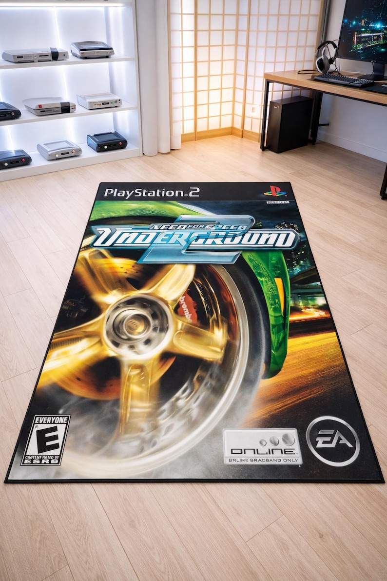 May include: A rectangular area rug featuring the Need for Speed Underground video game cover art for PlayStation 2. The design displays a close-up of a gold car wheel, the game title, the ESRB E rating, and the EA Online logo on a black background.