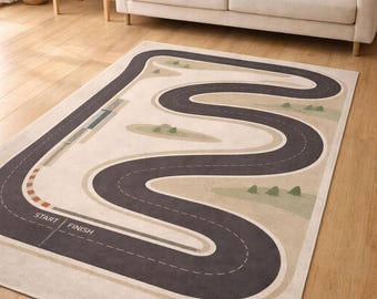 May include: A rectangular area rug featuring a printed dark gray winding racetrack design on a light beige background. The track includes white dashed lane markings, a start and finish line, and small green triangular shapes representing trees.