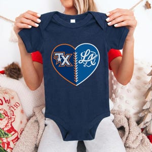 May include: Navy blue baby bodysuit with a heart-shaped design. The heart is split into two sections, one with "TX" in orange and white, and the other with "LA" in white. The bodysuit is short-sleeved.