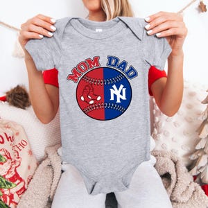 May include: A gray baby onesie with a baseball design. The baseball is split into red and blue halves, with a white sock and the New York Yankees logo. The words "MOM" and "DAD" are above the baseball.