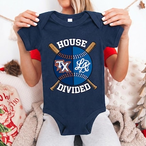 May include: Navy blue baby bodysuit with a baseball design. The design features a baseball split in half with the text "House Divided" and the letters "TX" and "LA" on each side, with crossed baseball bats.