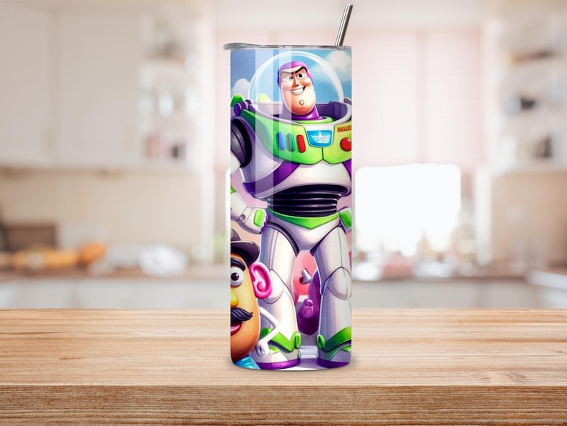 May include: A cylindrical stainless steel tumbler featuring a full-wrap graphic print of the character Buzz Lightyear in a white, green, and purple space suit, alongside a partial view of Mr. Potato Head. The tumbler includes a metal straw.