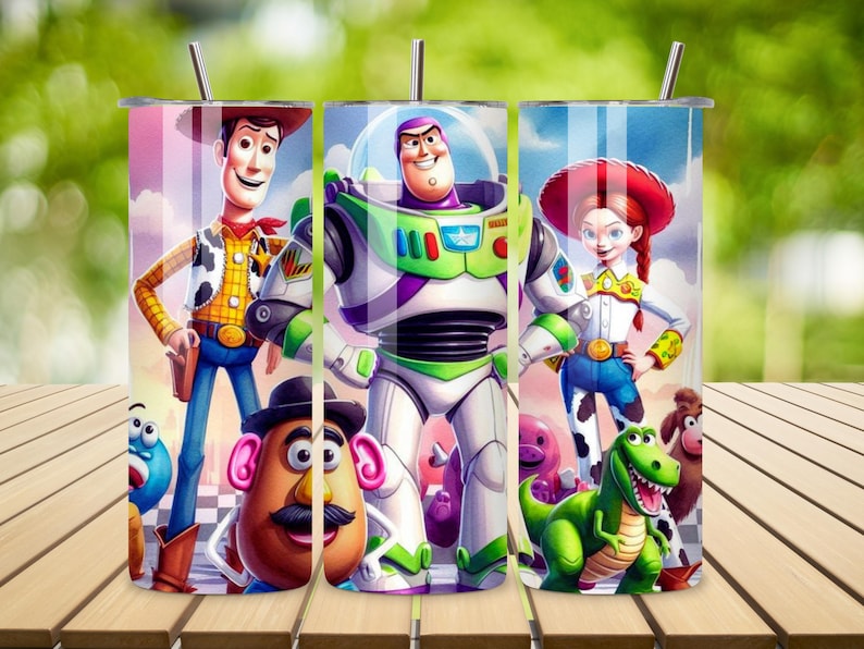 May include: A cylindrical tumbler featuring a colorful graphic print of characters from Toy Story, including Woody, Buzz Lightyear, Jessie, Mr. Potato Head, and Rex. The design includes a metal straw inserted into the lid, set against a blue sky background.
