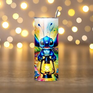 May include: A stainless steel tumbler featuring a colorful cartoon character holding a lantern. The design includes a blue alien-like creature with large eyes and antennae. The tumbler has a silver straw and a vibrant, multicolored background.