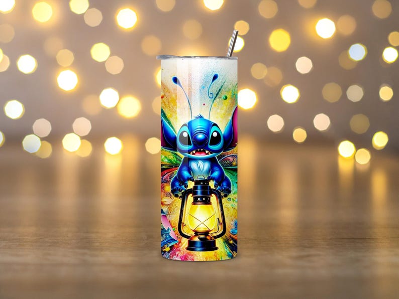 May include: A stainless steel tumbler featuring a colorful cartoon character holding a lantern. The design includes a blue alien-like creature with large eyes and antennae. The tumbler has a silver straw and a vibrant, multicolored background.