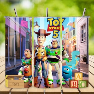 May include: A cylindrical metal tumbler featuring a colorful Toy Story 5 graphic print. The design displays characters including Woody, Buzz Lightyear, Rex, and Mr. Potato Head set against a street scene with a toy box and alphabet blocks.