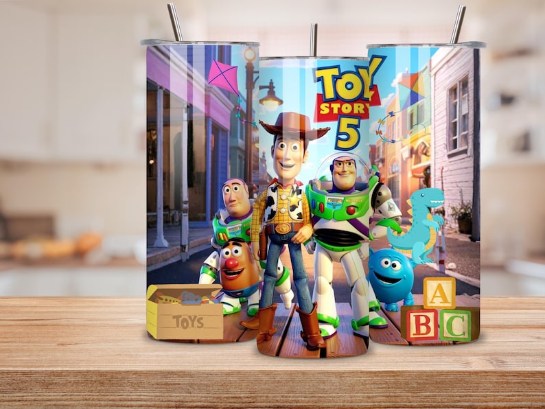 May include: A cylindrical metal tumbler featuring a colorful graphic print of characters from Toy Story 5, including Woody, Buzz Lightyear, Mr. Potato Head, and Rex. The design includes a toy box, alphabet blocks, and a street scene background.