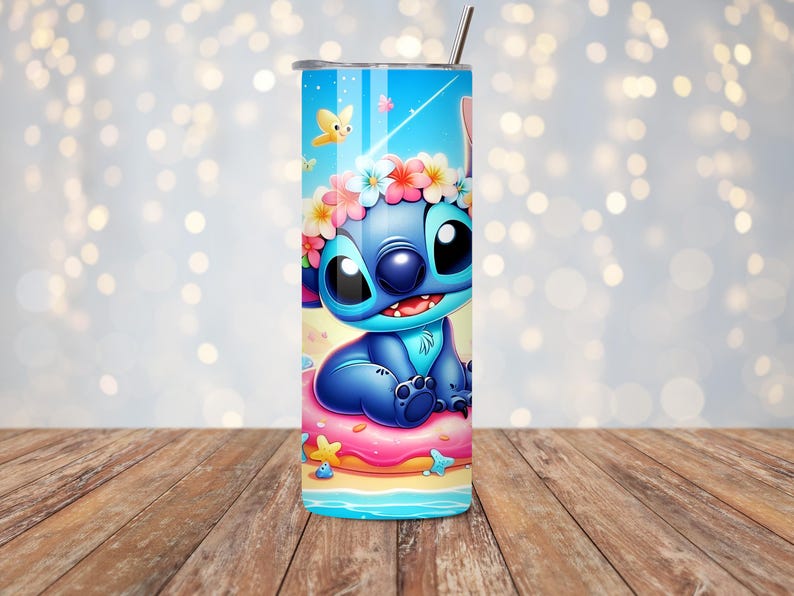 May include: A blue tumbler featuring a cartoon character with large black eyes, a flower crown, and a smiling expression. The tumbler has a blue background with butterflies and a beach scene. A silver straw is inserted into the lid.