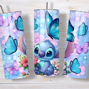 May include: A cylindrical stainless steel tumbler featuring a light blue background with a repeating pattern of blue and purple butterflies, pink and white flowers, and a central illustration of a blue alien character holding a pink flower.