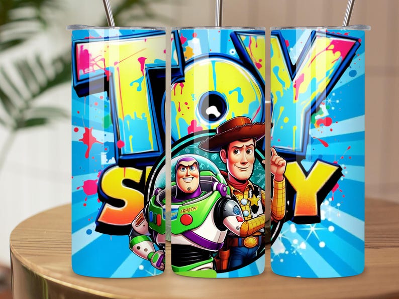 K&ouml;nnte beinhalten: Drei Edelstahlbecher mit einem farbenfrohen "TOY STORY" Design. Das Design zeigt Woody und Buzz Lightyear vor einem blauen Hintergrund mit radialen Linien und Farbspritzern. Jeder Becher hat ein Fassungsverm&ouml;gen von etwa 473 ml.