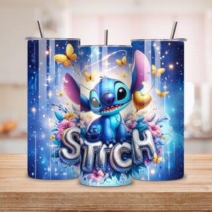 May include: Three blue tumblers with a whimsical design featuring the character Stitch, butterflies, and floral accents. The word "Stitch" is displayed in a bubble font. Each tumbler has a silver straw and a lid.