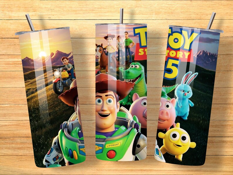May include: A cylindrical tumbler with a metal straw featuring a Toy Story 5 graphic print. The design displays characters including Woody, Buzz Lightyear, Rex, Hamm, and Ducky against a sunset landscape. The text Toy Story 5 is visible at the top.