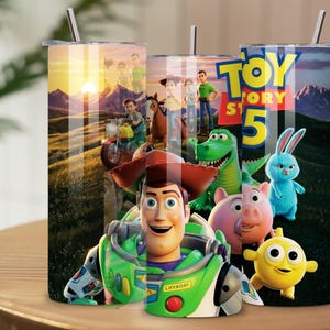 May include: Three cylindrical tumblers with metal straws featuring a Toy Story 5 graphic print. The design displays characters including Woody, Buzz Lightyear, Rex, Hamm, Ducky, and Bunny against a sunset landscape. The text Toy Story 5 is visible.