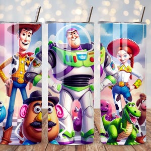 May include: A cylindrical stainless steel tumbler featuring a colorful wrap-around graphic of animated characters including a cowboy, a space ranger, a cowgirl, a potato-shaped figure, and a green dinosaur, topped with a thin metal straw.