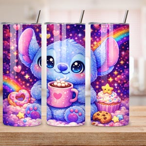 May include: Three stainless steel tumblers with a cartoon character design. The design features a blue creature holding a pink mug with a heart, surrounded by sweets, rainbows, and stars. The tumblers have a silver lid and a straw.