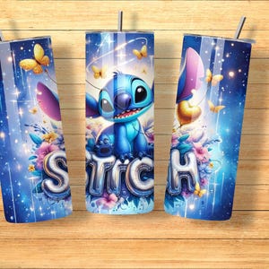 May include: Three blue tumblers with a Stitch design. The design features the character Stitch, butterflies, and the word "Stitch" in a bubble font. The tumblers have a silver straw and lid, set against a blue background with floral accents.