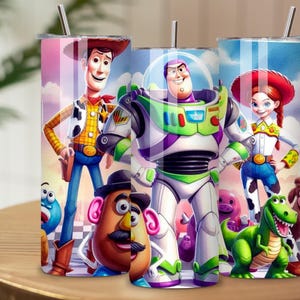 May include: Three cylindrical metal tumblers with silver straws, each featuring a colorful wrap-around print of animated characters including a cowboy, a space ranger, a cowgirl, a potato-shaped figure, and a green dinosaur against a blue sky.