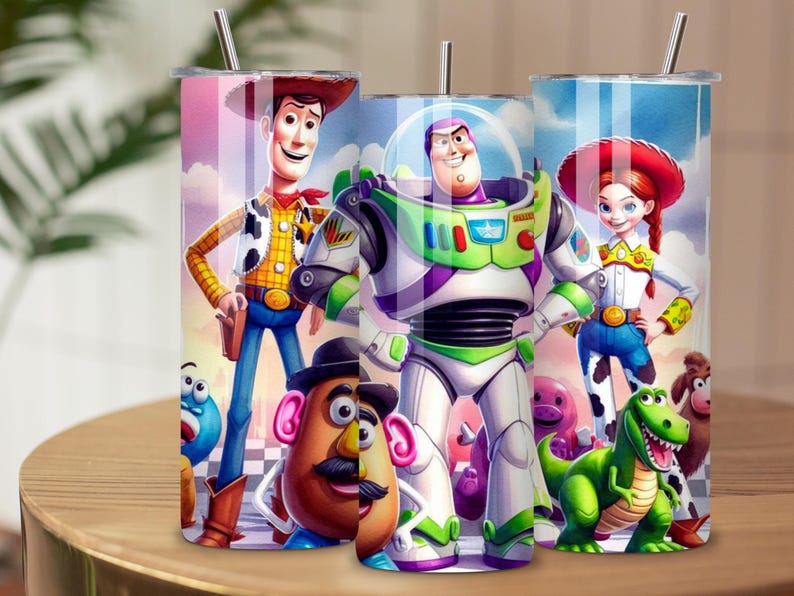 May include: Three cylindrical metal tumblers with silver straws, each featuring a colorful wrap-around print of animated characters including a cowboy, a space ranger, a cowgirl, a potato-shaped figure, and a green dinosaur against a blue sky.